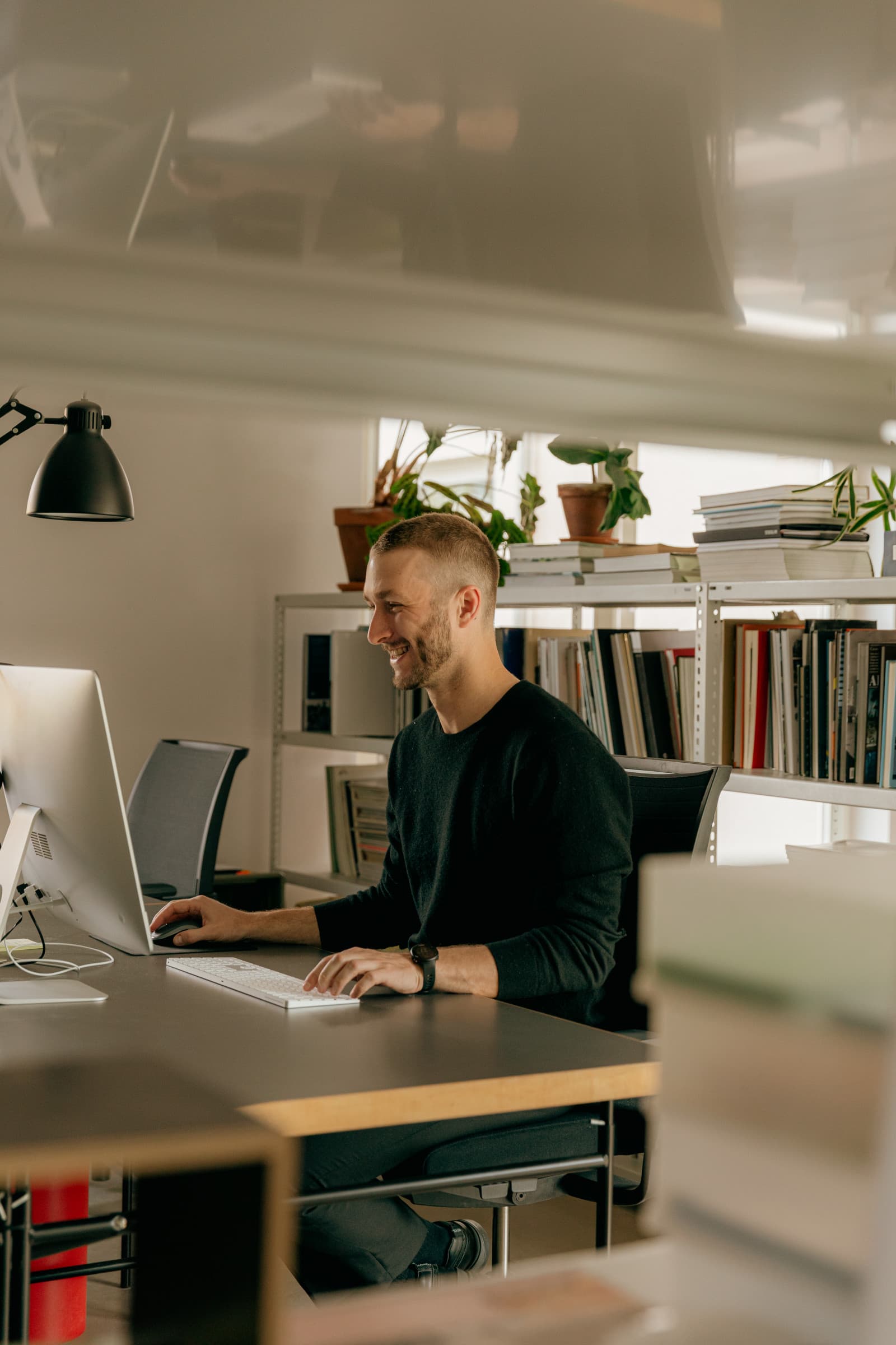 Leende person som arbetar vid datorn på ett kontor